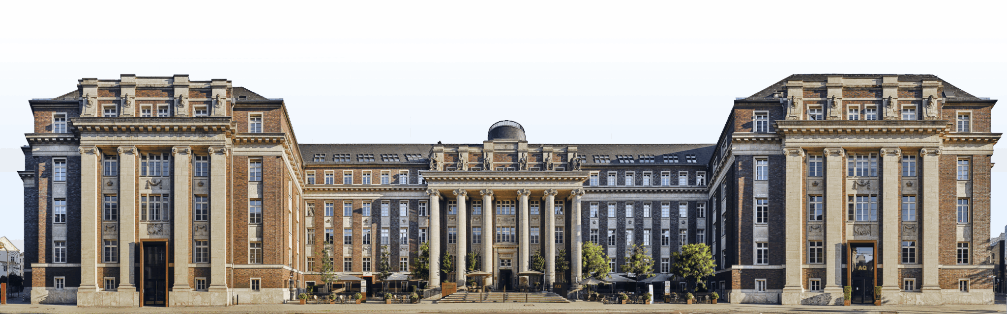 Panoramafotografie der historischen Fassade des Luxushotels The Wellem in Düsseldorf mit monumentalen Säulen, symmetrischer Architektur und klassizistischen Details bei klarem Tageslicht.