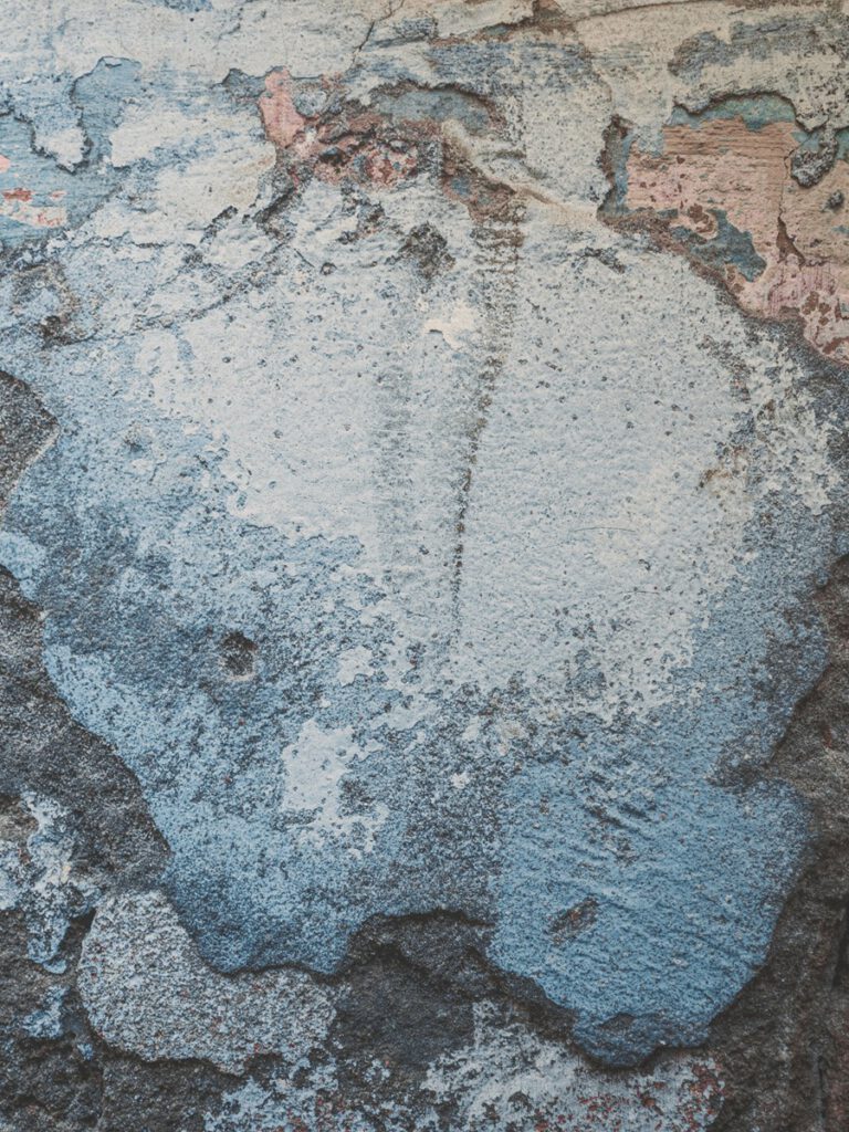 Abstraktes Wandkunstwerk im Hotel The Wellem Düsseldorf mit strukturierter, mehrfarbig verwitterter Oberfläche in Blau-, Grau- und Rosétönen.
