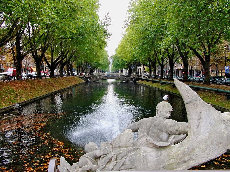Blick über den Kö-Graben mit Baumallee und Tritonenbrunnen unweit des Hotel The Wellem Düsseldorf.