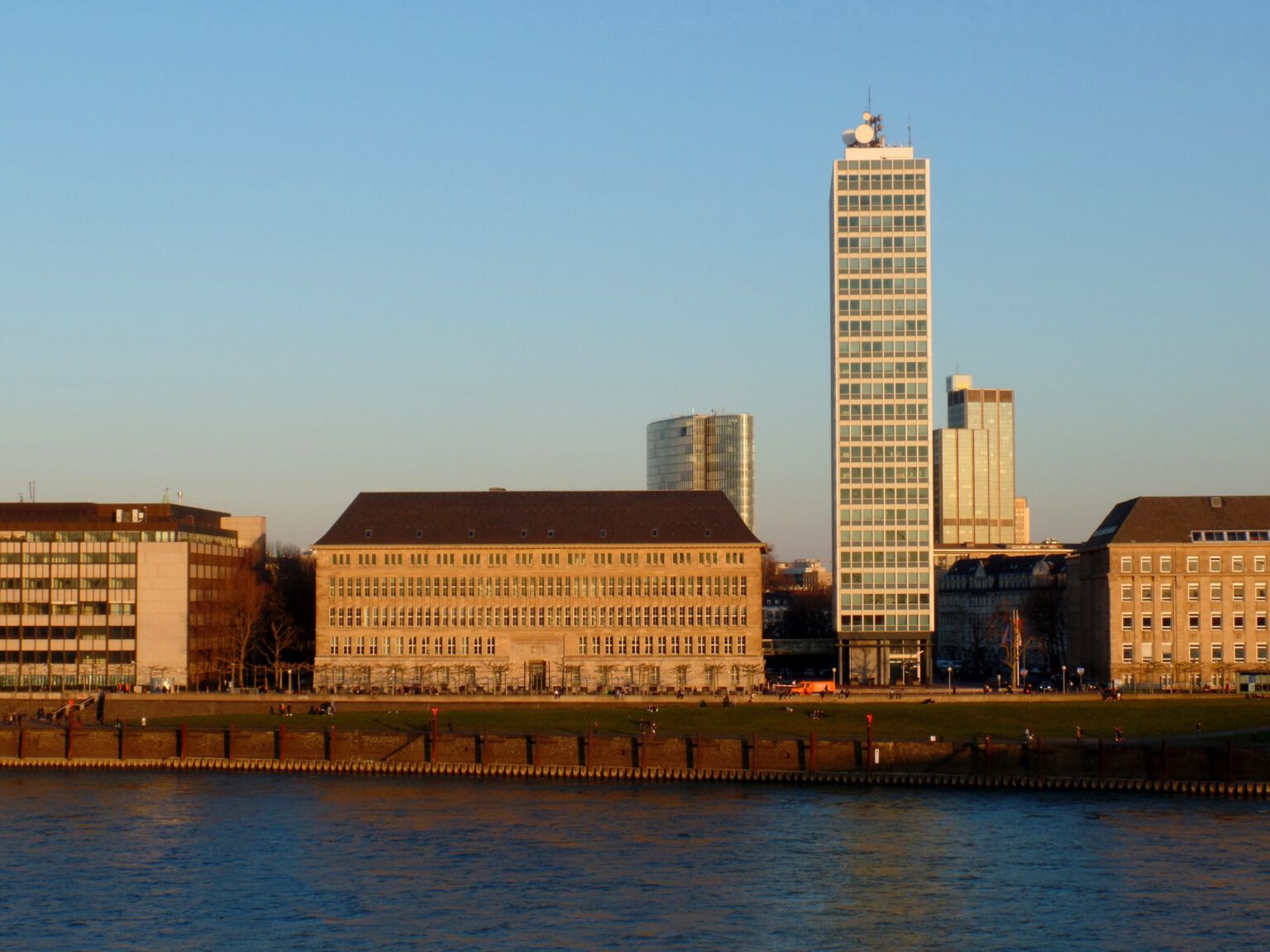 Blick auf die Rheinuferpromenade mit dem markanten Hochhaus des Düsseldorfer Rathauses im warmen Abendlicht in der nähe des Hotel The Wellem.