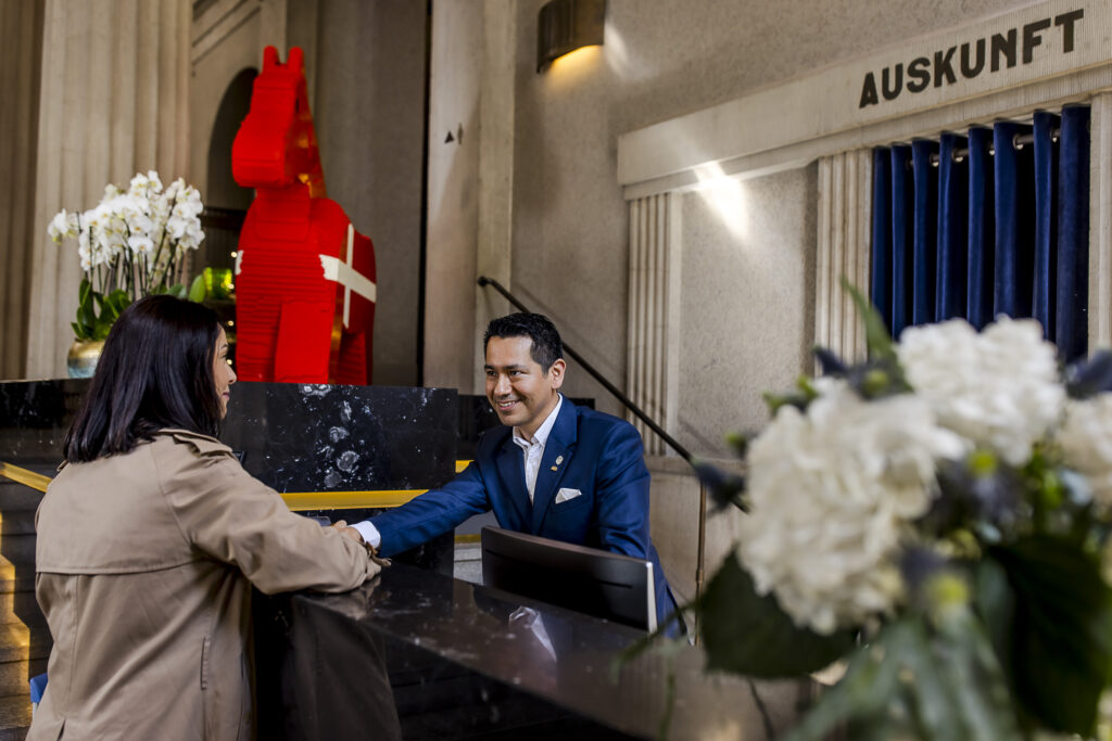Concierge staff of Hotel The Wellem in Düsseldorf welcomes a hotel guest at the reception.